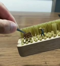 a toothbrush holder with miniature people on it and grass in the shape of horses