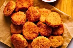 some fried food sitting on top of a piece of paper next to a bowl of sauce