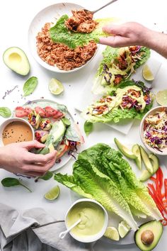 two people are eating lettuce wraps with dressing and dipping sauces on the side