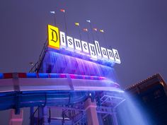 the disneyland land sign is lit up at night with colorful lights on it's sides