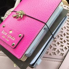 a pink notebook sitting on top of a purse