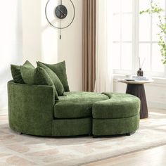 a living room with a large green sectional couch and clock on the wall above it