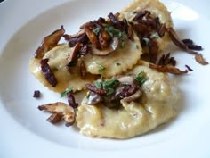 two ravioli with mushrooms and cheese on a white plate