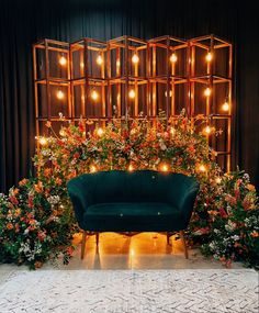 a green couch sitting in front of a wooden wall with lights hanging from it's sides