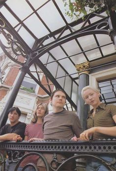 four people sitting on a bench in front of a building