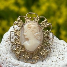 Vintage carved cameo brooch on a gold tone metal prong set setting. This is a small cameo measuring approximately 1 and 1/4" from top to bottom and 1" across. The pin and latch are in good working order. The cameo feels secure in the prong settings. This is unsigned but a lovely carved left facing cameo! Please see all photos and if have any additional questions please message me! Thank you for looking! Carved Gold Brooch For Gift, Carved Gold Brooches As Gifts, Ornate Carved Gold Brooches, Ornate Gold Carved Brooches, Collectible Carved Gold Brooches, Ornate Cameo Brooch For Anniversary, Ornate Cameo Brooches For Anniversary, Gold Cameo Brooch For Wedding, Gold Oval Cameo Brooch