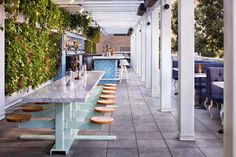 an outdoor bar with lots of seating and plants growing on the wall next to it