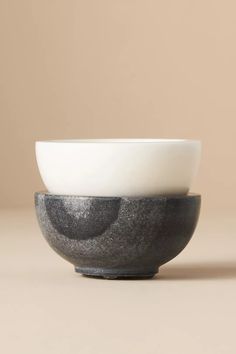 two black and white bowls sitting side by side on a beige surface with one bowl in the middle