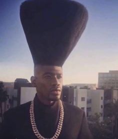 a man with a weird hat on his head standing in front of a cityscape