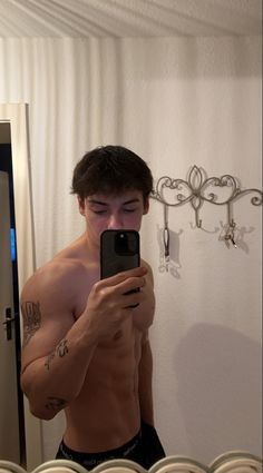 a shirtless man taking a selfie in front of a mirror with his cell phone