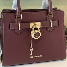 Compact Yet Practical, This Small Satchel Bag Is The Ideal Daily Companion. Polished Mk Lock And Key Make A Luxe Statement! Zip Closure Double Handle Michael Kors Hamilton Small Leather Satchel Crossbody Bag (Merlot) With Gold Tone Hardware Interior Detail: Custom Michael Kors Fabric Lining, 1 Slip Pocket, And 1 Zip Pocket Mk Key & Lock-On Front, Double Handle Drop 4" With Adjustable Crossbody Strap Included Measurements Are Approx. 10" (L) X 8"(H) X 4"(D) No Dust Bag Evening Burgundy Bag With Branded Hardware, Formal Burgundy Bags With Metal Hardware, Burgundy Evening Bag With Branded Hardware, Luxury Burgundy Bags With Metal Hardware, Elegant Purple Bags With Gold-tone Hardware, Luxury Purple Bag With Branded Hardware, Modern Michael Kors Bags With Gold-tone Hardware, Merlot Color, Michael Kors Bags With Gold-tone Hardware For On-the-go