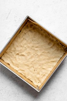 a square pan filled with batter on top of a white counter next to a knife