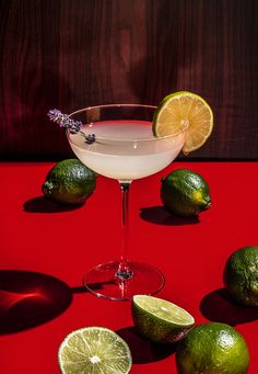 a martini with limes and lavender on a red table