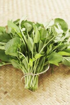 a bunch of green leafy vegetables on a woven tablecloth with some string tied around it