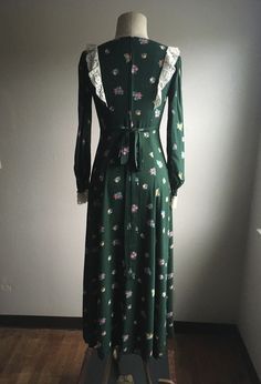 "1970s handmade prairie dress cotton w/lace trim zip up back ties below bust front to back long sleeve w/elastic wrist cuff dark green w/multi-color floral pattern very good vintage condition, light wear no size label tag (measures like xs/s but please go by measurements) measures, lying flat, shoulder-14 1/2\" bust-16 1/2\" waist-14\" hip-22 1/2\" sleeve-23\" length-51\"" Vintage Dresses With Lace Trim For Fall, Vintage Fall Dresses With Lace Trim, Green Lace Trim Dress For Fall, Fitted Cottagecore Dress For Fall, Fitted Long Sleeve Dress With Vintage Print, 1970s Style Long Sleeve Dresses For Spring, Long Sleeve Dresses For Vintage Fashion In Spring, Vintage Long Sleeve Green Dress, Green Long Sleeve Cottagecore Dress