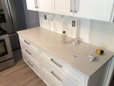 a kitchen counter with white cabinets and silver appliances in the back drop off area next to it