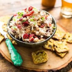 a bowl filled with food sitting on top of a wooden board next to crackers