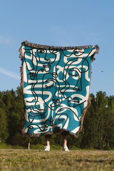 a person standing in the grass with a blue and white blanket