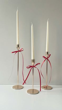 three white candles with red ribbons tied around them