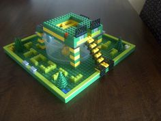 a green lego table with yellow and black pieces on it's top, in the middle of a room