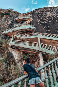 a woman walking up some stairs next to a mountain