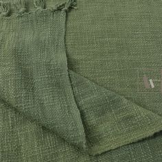 the fabric is green and has fringes on top of it, as well as a square