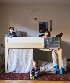 two children are sitting on the bottom bunk of a bed, while one child is playing with a toy