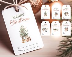 merry christmas gift tags with ornaments and baubles on a wooden table next to a pine tree