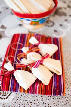 small pieces of food are on a table cloth next to a bowl and spoons