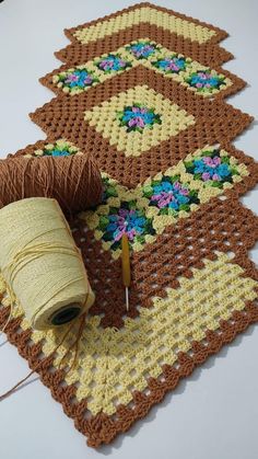 two crocheted placemats with yarn and thread on the table next to each other