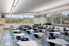 an empty classroom with desks and chairs in front of large windows looking out on trees