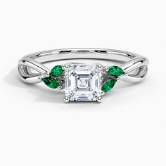 an emerald and white gold engagement ring with leaves on the band, set in 18k white gold