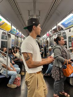 a man with tattoos on his arm standing next to a woman in a subway car