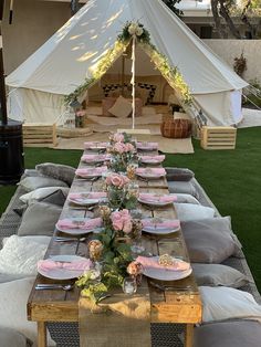 a table set up with plates and place settings in front of a teepee tent