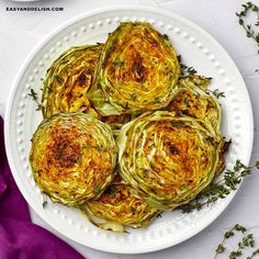 an overhead view of cooked artichokes on a white plate with purple linen