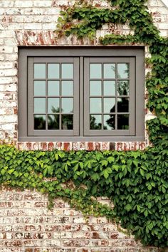 an old brick building with ivy growing on it's side and two windows in the middle