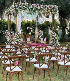 a bunch of chairs that are sitting in the grass with some flowers on top of them