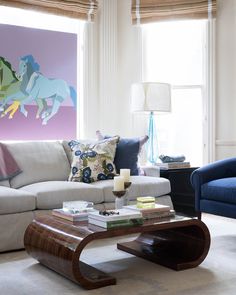 a living room with two couches and a coffee table in front of a painting