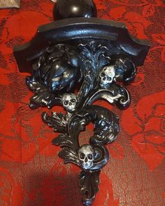 a clock with skulls on it sitting on a red tablecloth next to a black ball