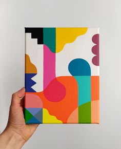 a hand holding up a colorful box with abstract designs on it's sides and bottom