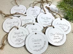 six white tags with the names and date on them hanging from twine strings next to a christmas tree