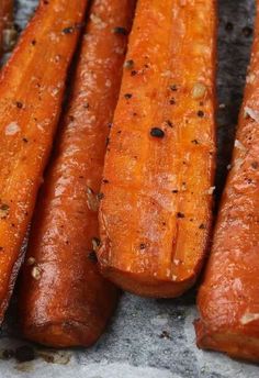 three carrots sitting on top of a table covered in seasoning next to each other