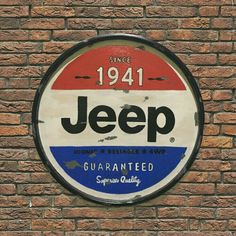 a sign on the side of a brick wall that says jeep and has been painted red, white, and blue