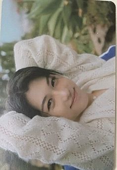 an old photo of a woman wrapped up in a white blanket and looking at the camera