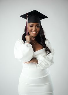 a woman in a graduation cap and gown posing for the camera with her hands on her chin