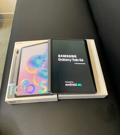 two samsung phones are sitting next to each other on a black table with an unopened box