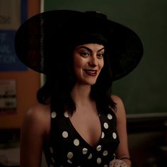 a woman wearing a polka dot dress and black hat