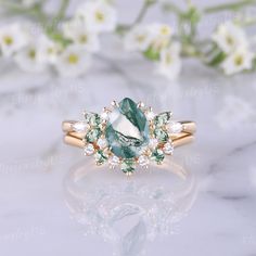 an oval cut green and white diamond ring on a marble surface with flowers in the background