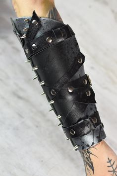 Post Apocalyptic Spiked Bracer - Wasteland Armor - Leather Arm Bracers - Heavy Metal Cuff - Armguard Armor Set - LARP - Stage Costume  Leather bracers, perfect for any LARP, photoshoot or as a stage costume. Great for post-apocalyptic, steampunk or fantasy settings.  Please feel free to ask for custom requests! Measures 9,84 inches in length (25cm), fitted for wrist with circumference minimum 6,29 inches (16 cm), regulated by belts. More clothes: https://www.etsy.com/shop/WastedCouture?section_id=18024503&ref=shopsection_leftnav_1 More accessories: https://www.etsy.com/shop/WastedCouture?section_id=18025607&ref=shopsection_leftnav_2 MORE CYBERPUNK FASHION: https://www.etsy.com/shop/WastedCouture?ref=seller-platform-mcnav&section_id=46065121  Wear if you dare! Postapoc Armor - Metal Arm Bra Wasteland Armor, Leather Arm Bracers, Styl Emo, Apocalyptic Steampunk, Arm Bracers, Fantasy Settings, Apocalypse Gear, Post Apocalyptic Costume, Leather Bracers