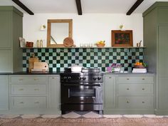 a stove top oven sitting inside of a kitchen next to green cupboards and counter tops